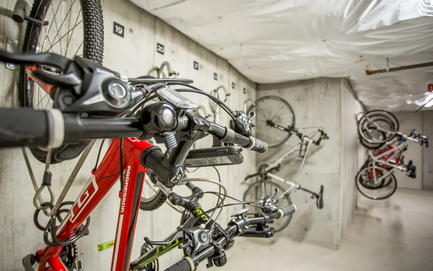 Indoor bike storage room with multiple bicycles mounted on wall racks.