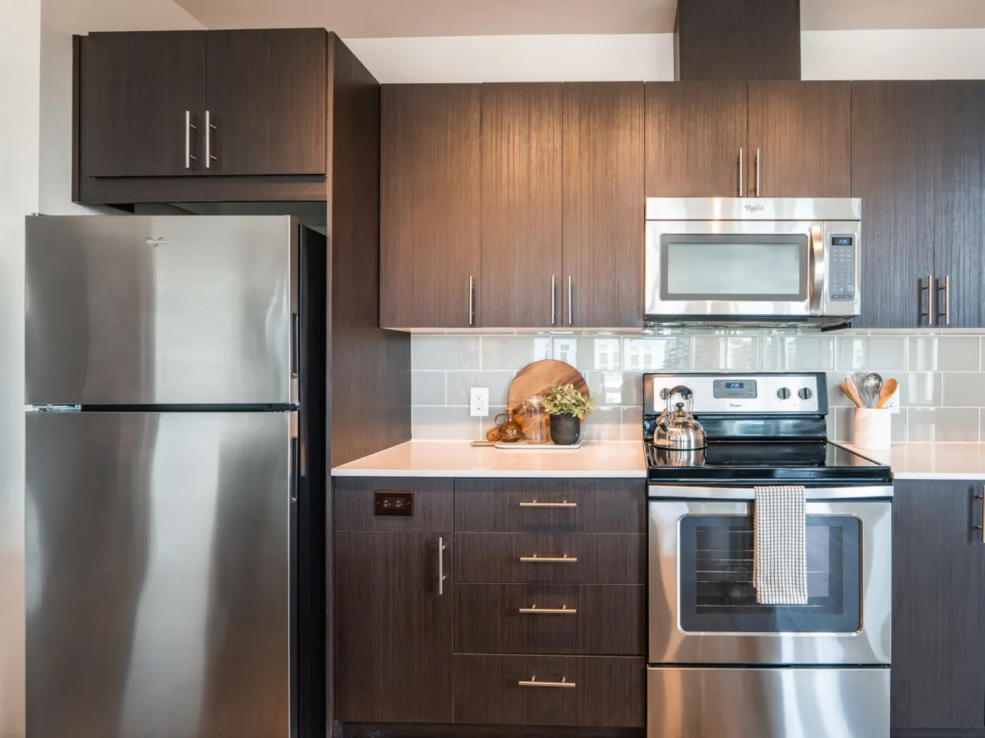 Modern kitchen in an apartment with stainless steel appliances and dark wood cabinets.
