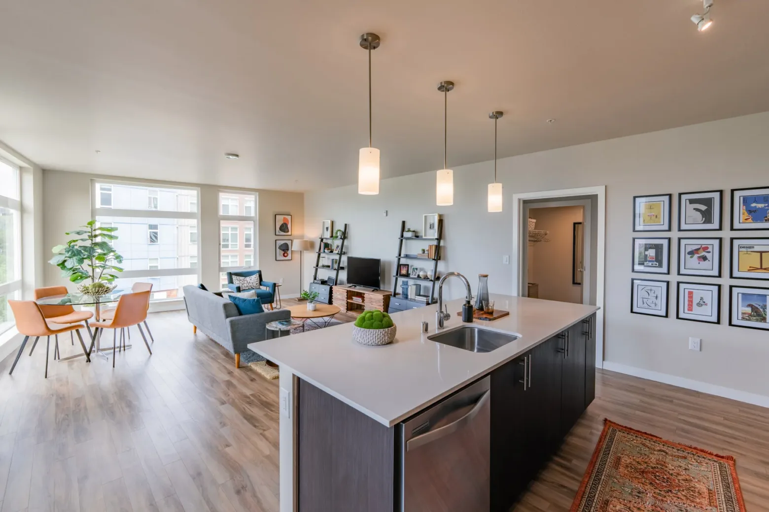 Spacious modern apartment interior with a kitchen island, a cozy seating area, and large windows.